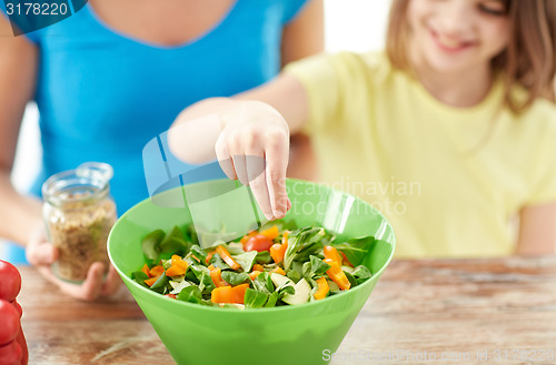 Image of close up of happy family cooking salad in kitchen