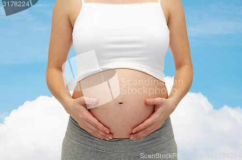 Image of close up of pregnant woman touching her bare tummy