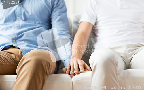 Image of close up of happy male gay couple holding hands