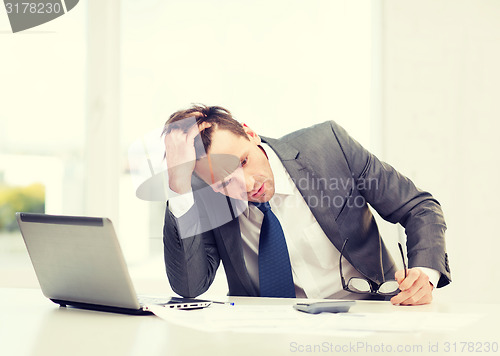 Image of businessman with computer, papers and calculator