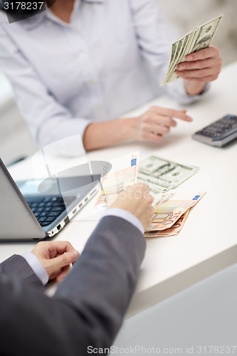 Image of close up of hands counting money with calculator