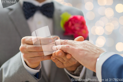 Image of close up of male gay couple hands and wedding ring