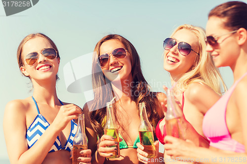 Image of group of smiling young women drinking on beach
