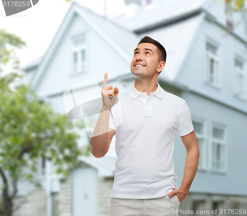 Image of man pointing finger up over house background