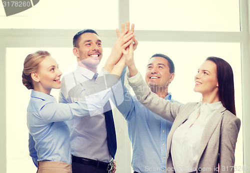 Image of happy business team giving high five in office