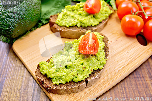 Image of Sandwich with guacamole avocado and tomato on dark board