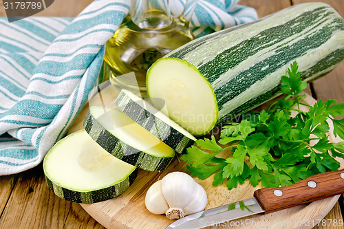 Image of Zucchini green striped with garlic and oil on board