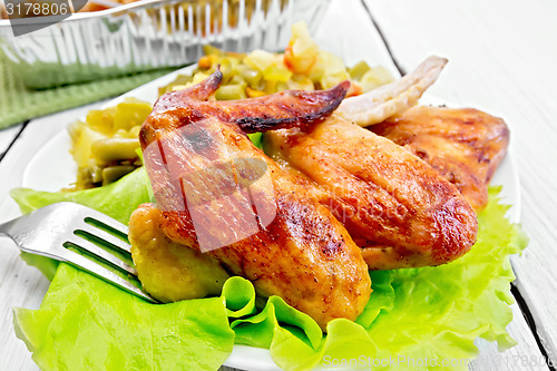 Image of Chicken wings fried with salad in plate on board