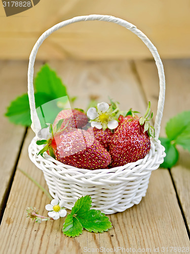 Image of Strawberries in basket with flowers and leaves on board