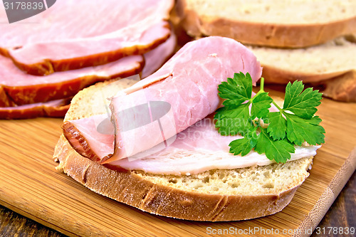 Image of Sandwich with ham and parsley on board