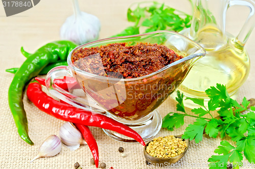 Image of Adjika in glass gravy boat with oil on sacking