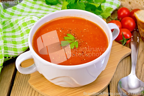Image of Soup tomato in bowl with spoon on board