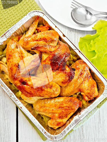 Image of Chicken wings fried with vegetables in pan from foil