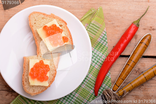 Image of sandwich with red caviar on white plate