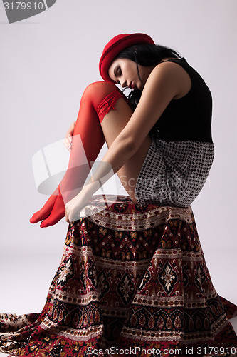 Image of Young woman in a hat, sitting on a chair