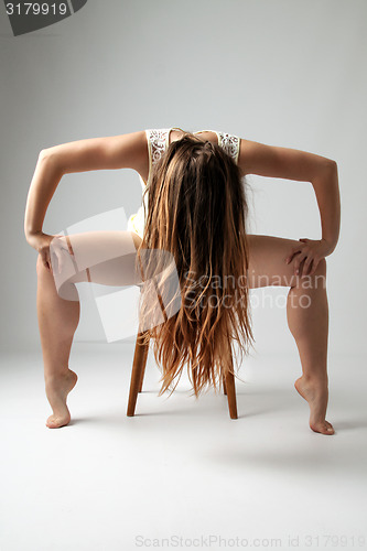 Image of Young woman sitting on a chair in ballet pose
