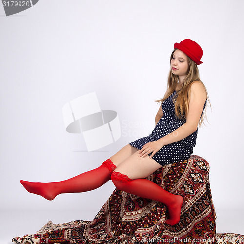 Image of Young woman in a hat, sitting on a chair