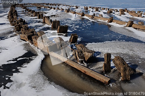 Image of remains of a wooden pier on the lake in winter