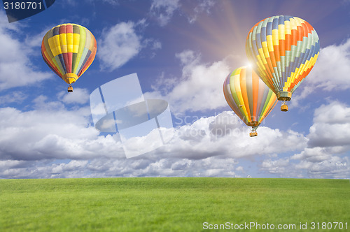 Image of Hot Air Balloons In Beautiful Blue Sky Above Grass Field 