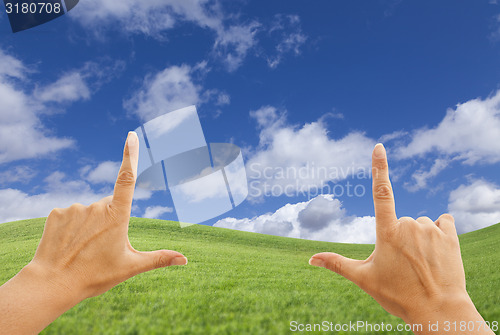 Image of Female Hands Framing Deep Blue Sky Above Grass Field
