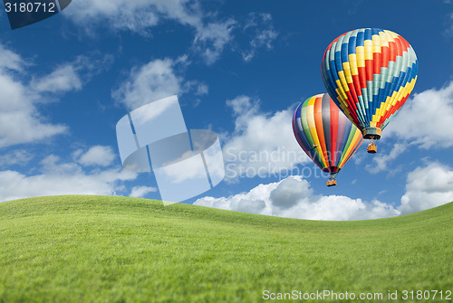 Image of Hot Air Balloons In Beautiful Blue Sky Above Grass Field 