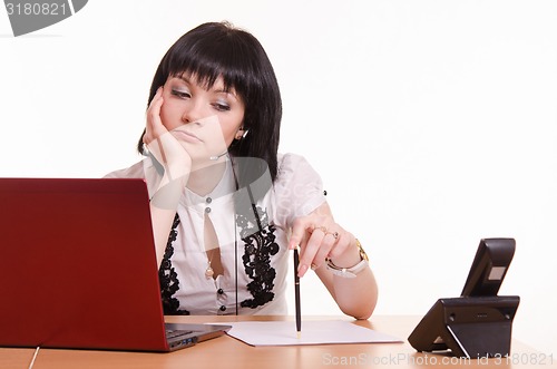 Image of Thoughtful call-center employee office with pen in hand