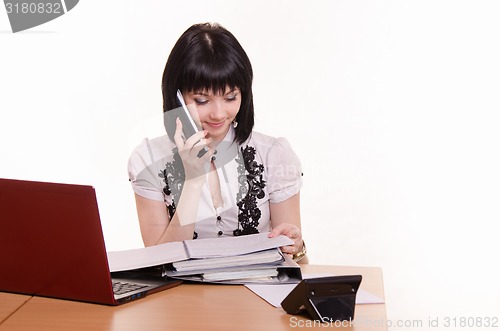Image of Office employee call-center talking on the phone, looking at paper