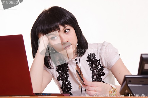 Image of Thoughtful employee call-center front of monitor leaned her head on