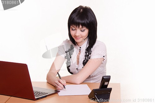 Image of Call-center employee at his desk writes