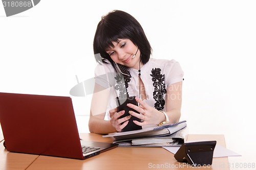 Image of Call-center worker with phone and a pile of papers