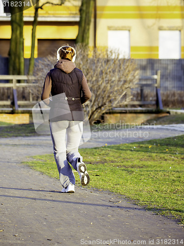 Image of young woman with headphones jogging in park