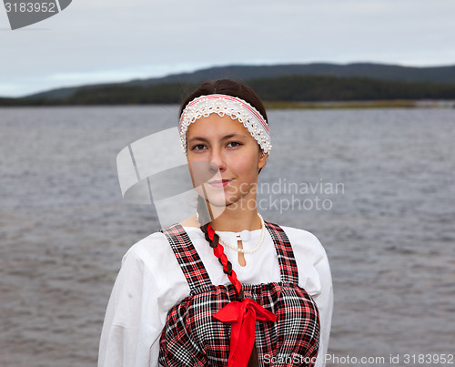 Image of Young girl in national dress at the river shore