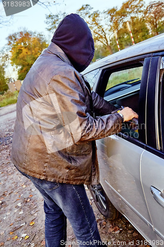 Image of Hooligan breaking into car