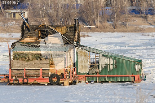 Image of Burnt wooden structure standing on ice of river