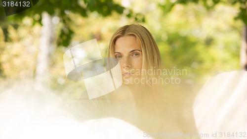 Image of portrait of a beautiful young woman in park.