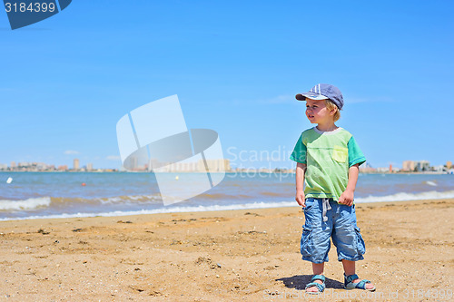 Image of Small trendy boy standing sandy beach