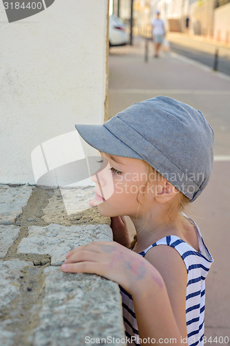 Image of Little girl looking through a wall