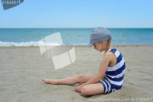 Image of Very serious cute little girl sitting on the beach
