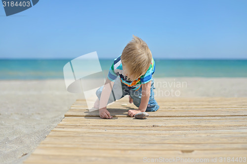 Image of Small boy playing with stones on the beach