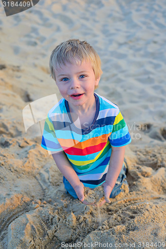Image of Little toddler boy sitting sandy beach