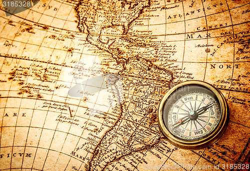 Image of Vintage compass lies on an ancient world map.