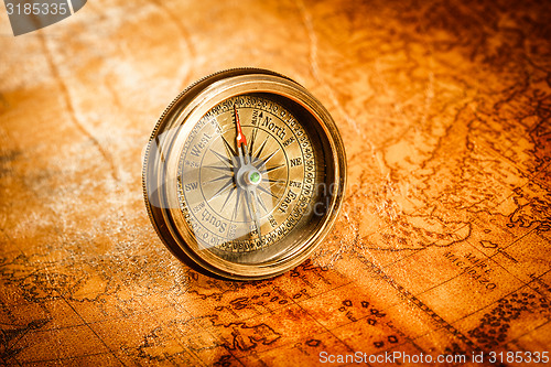 Image of Vintage compass lies on an ancient world map.