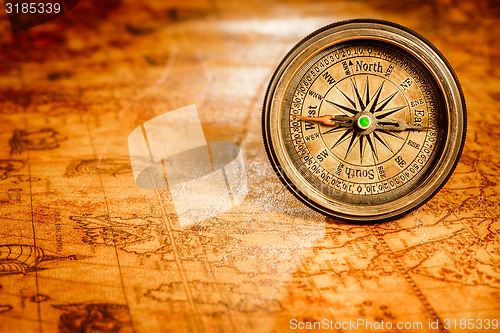 Image of Vintage compass lies on an ancient world map.