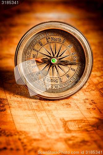 Image of Vintage compass lies on an ancient world map.