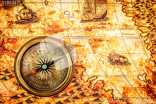 Image of Vintage compass lies on an ancient world map.