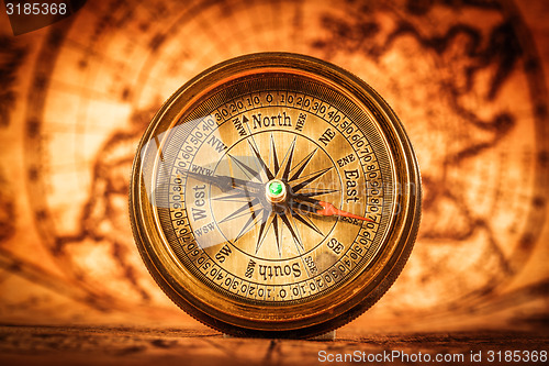 Image of Vintage compass lies on an ancient world map.