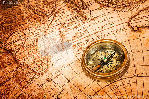 Image of Vintage compass lies on an ancient world map.