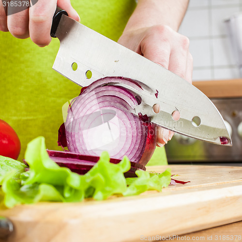 Image of Woman\'s hands cutting bulb onion