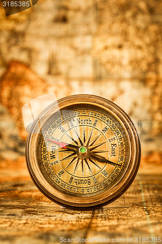 Image of Vintage compass lies on an ancient world map.