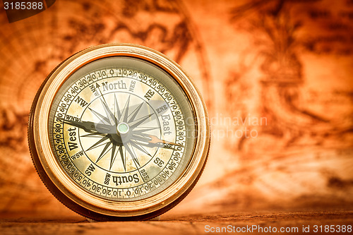 Image of Vintage compass lies on an ancient world map.